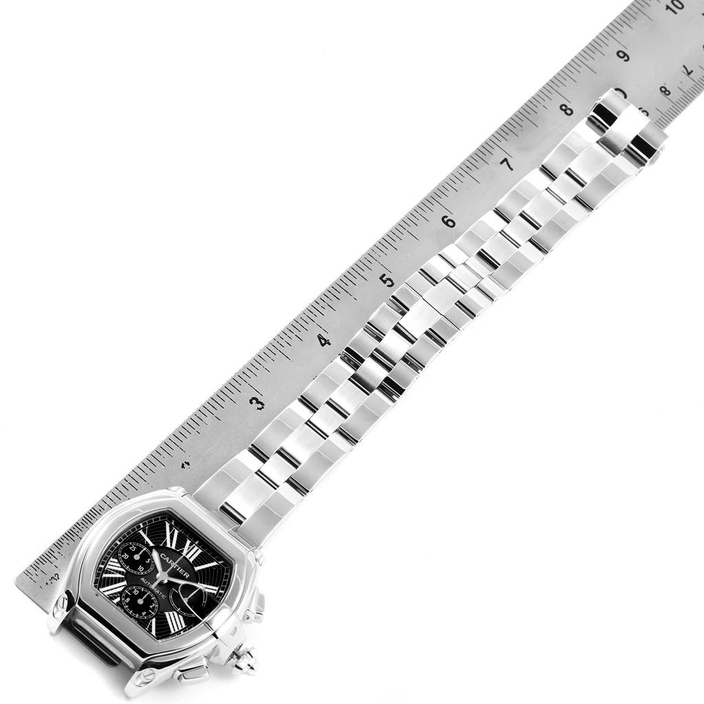 The image shows a Cartier Roadster W62020X6 Men
s Stainless Steel Black Dial W62020X6 Men
s Stainless Steel Black Dial watch laid flat next to a ruler, displaying the face and metal bracelet.