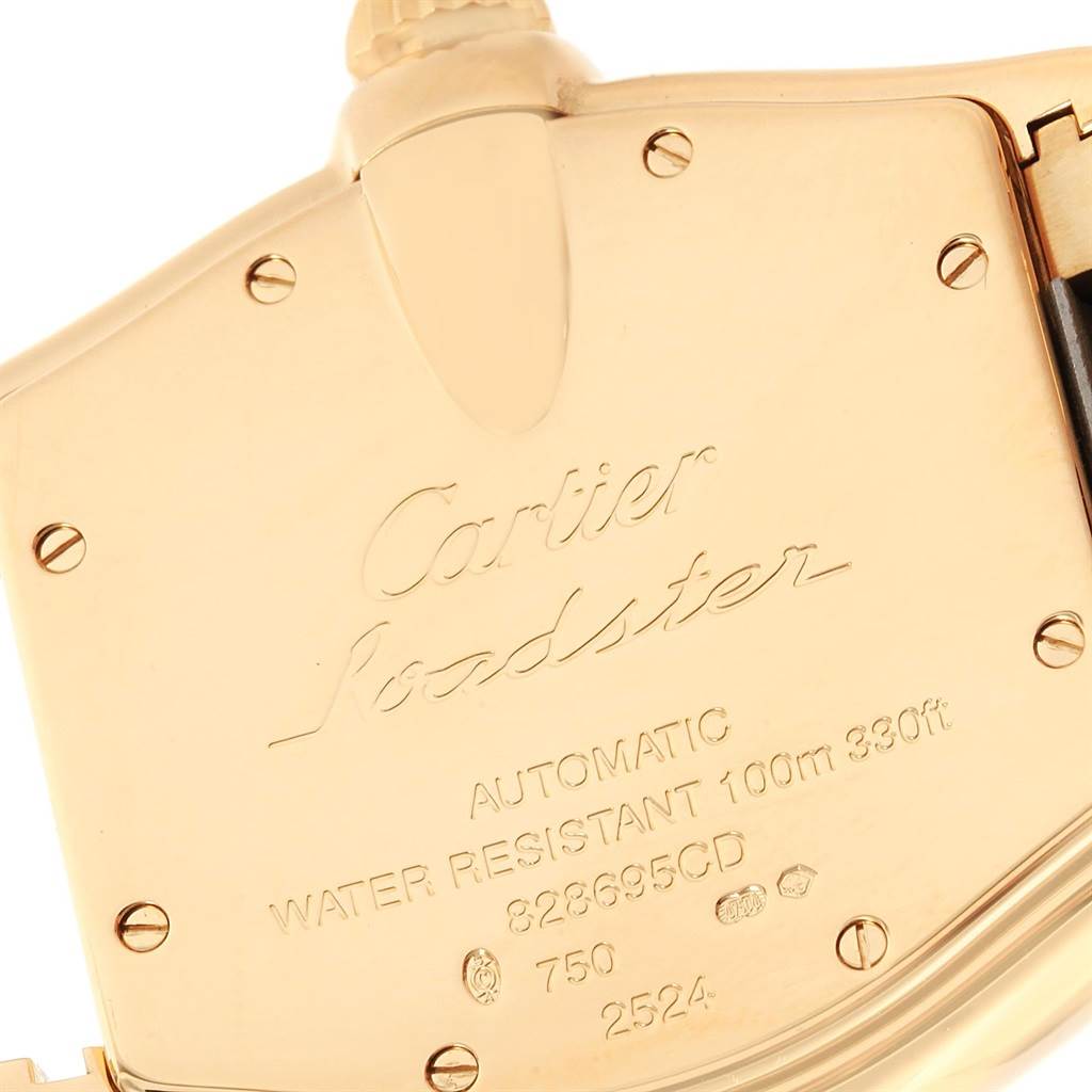 The image shows a close-up of the back case of a Cartier Roadster W62005V1 Men's Yellow Gold Silver Dial W62005V1 Men's Yellow Gold Silver Dial watch, highlighting its engravings and gold finish.