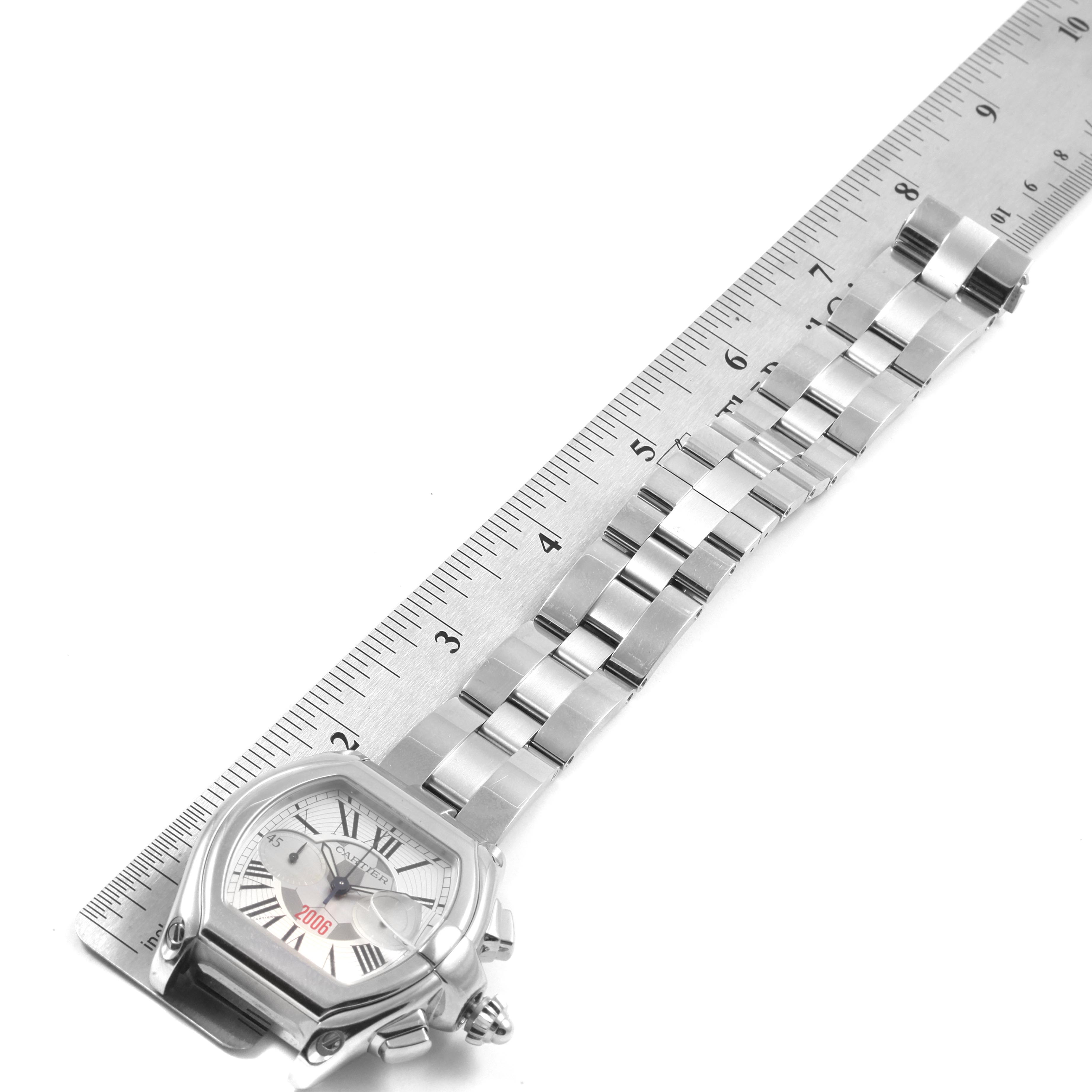 The Cartier Roadster W62044X6 Men's Stainless Steel Silver Dial W62044X6 Men's Stainless Steel Silver Dial watch is shown flat with a metal ruler, displaying its face and extended metal strap.