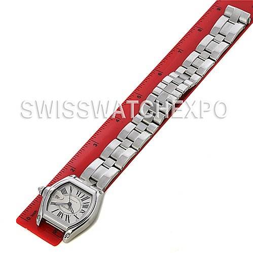 The Cartier Roadster W62025V3 Men's Stainless Steel Silver Dial W62025V3 Men's Stainless Steel Silver Dial watch is shown lying flat, displaying its face, bracelet, and part of a red measuring ruler.
