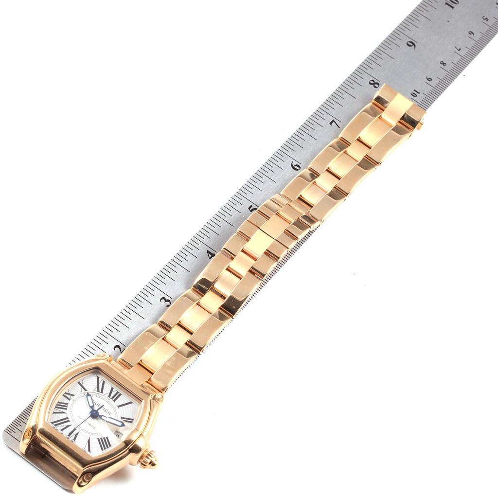 The image shows a Cartier Roadster W62005V1 Men's Yellow Gold Silver Dial W62005V1 Men's Yellow Gold Silver Dial watch laid flat on its face beside a ruler, displaying the watch's case, dial, and bracelet.