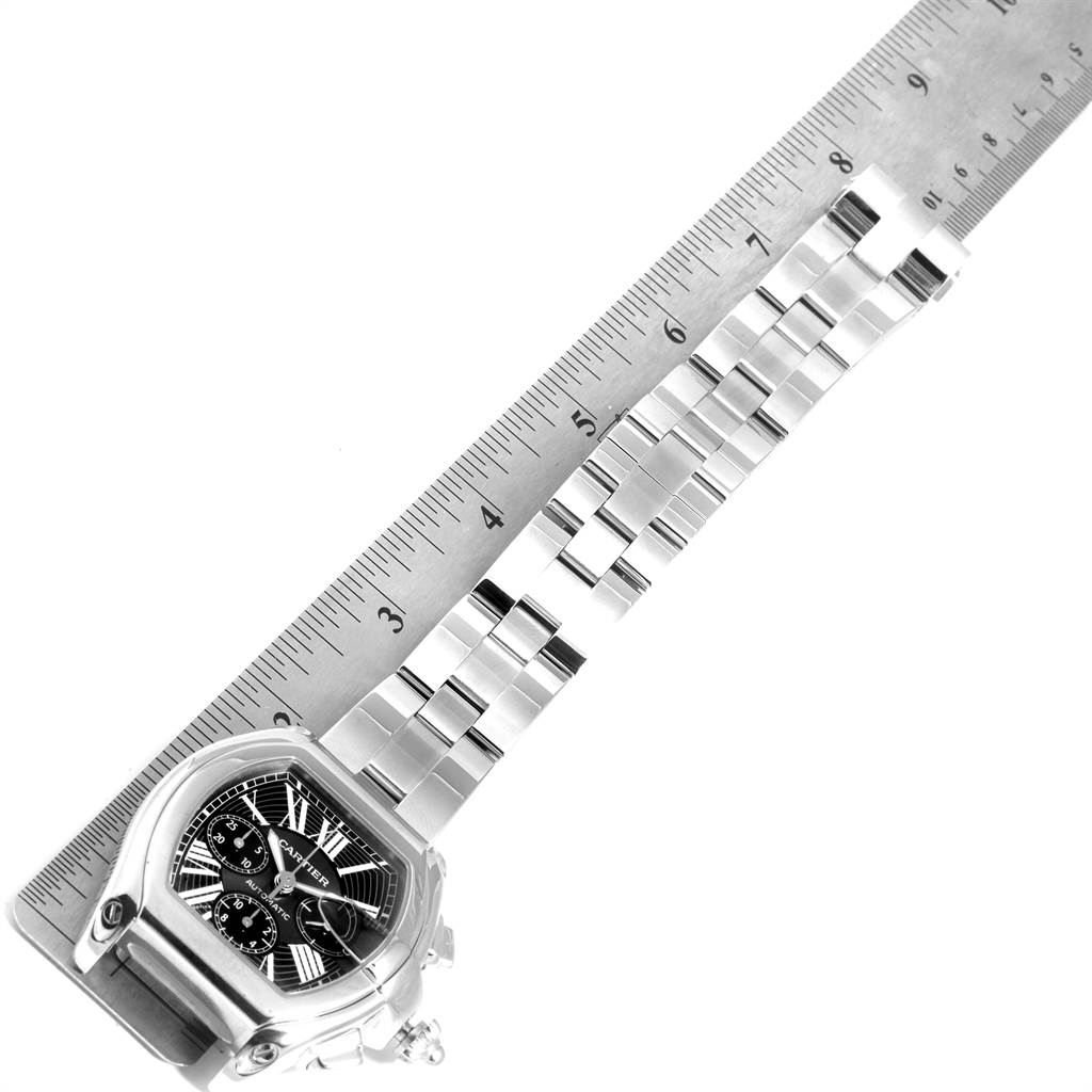 The Cartier Roadster W62020X6 Men's Stainless Steel Black Dial W62020X6 Men's Stainless Steel Black Dial watch is shown in an angled top-down view, featuring the face, bezel, and bracelet, alongside a ruler for scale.