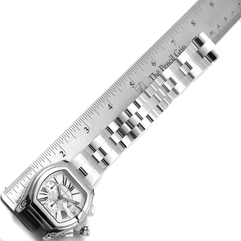 The image shows the Cartier Roadster W62019X6 Men's Stainless Steel Silver Dial W62019X6 Men's Stainless Steel Silver Dial model watch and its stainless steel bracelet laid out next to a ruler.