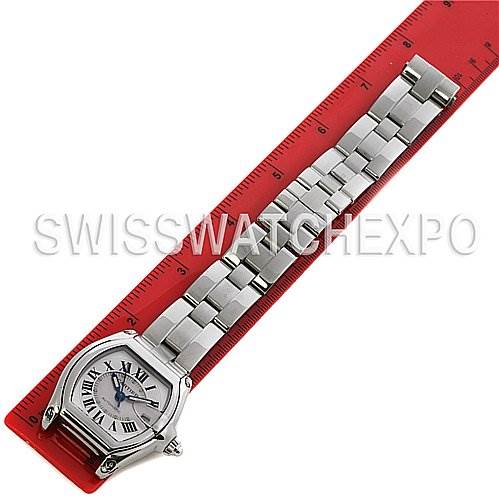 The image shows a top-down view of a Cartier Roadster W62025V3 Men's Stainless Steel Silver Dial W62025V3 Men's Stainless Steel Silver Dial watch placed next to a red ruler displaying its bracelet and face.
