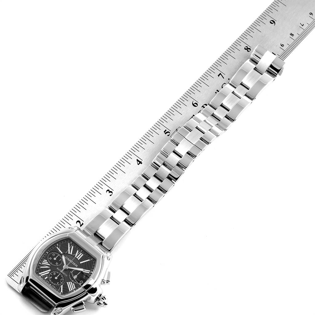 The image shows the Cartier Roadster W62020X6 Men
s Stainless Steel Black Dial W62020X6 Men
s Stainless Steel Black Dial watch face and bracelet laid flat next to a ruler, capturing a top-down angle.