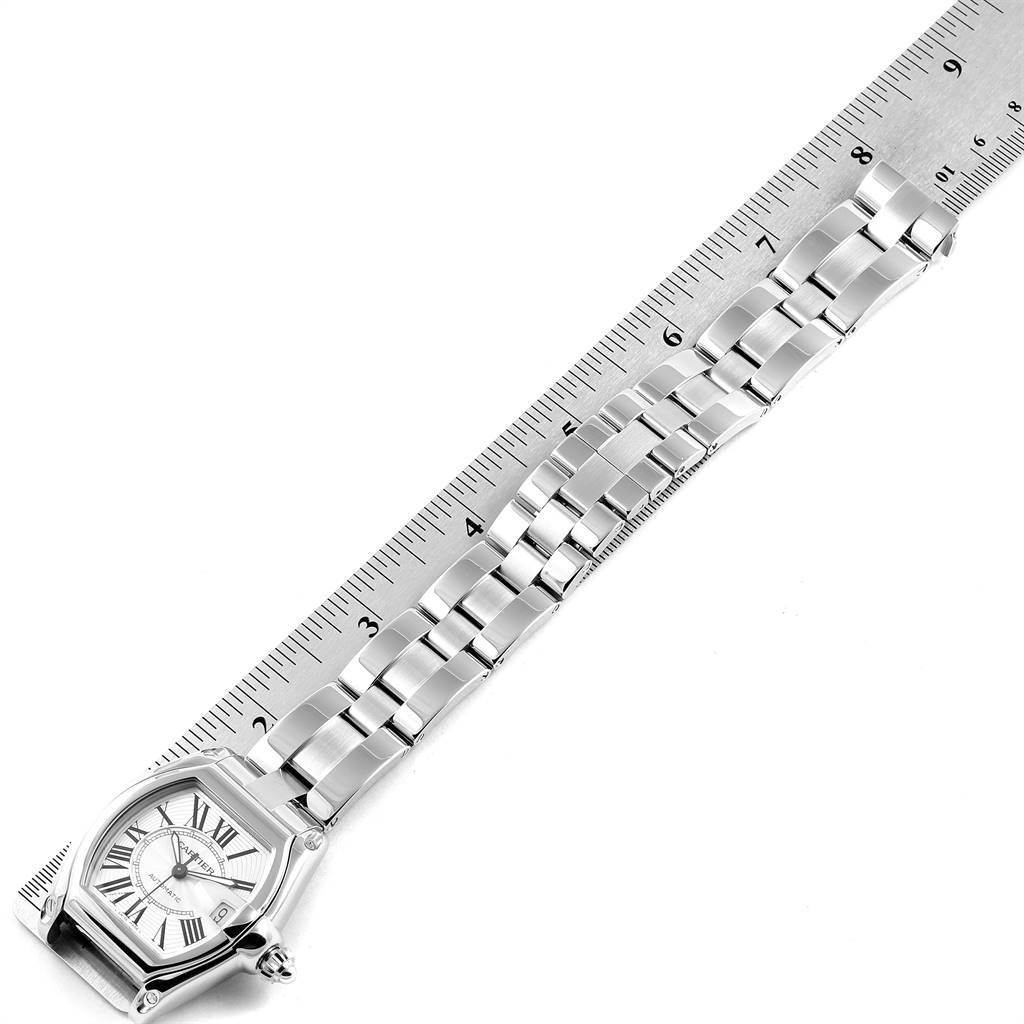 The image shows the Cartier Roadster W62025V3 Men's Stainless Steel Silver Dial W62025V3 Men's Stainless Steel Silver Dial watch and stainless steel bracelet laid flat against a ruler, viewed from above.