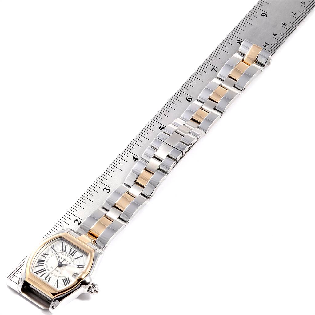 The image shows a Cartier Roadster W62031Y4 Men's Steel and Gold (two tone) Silver Dial W62031Y4 Men's Steel and Gold (two tone) Silver Dial watch placed next to a ruler, highlighting its face and full length strap.