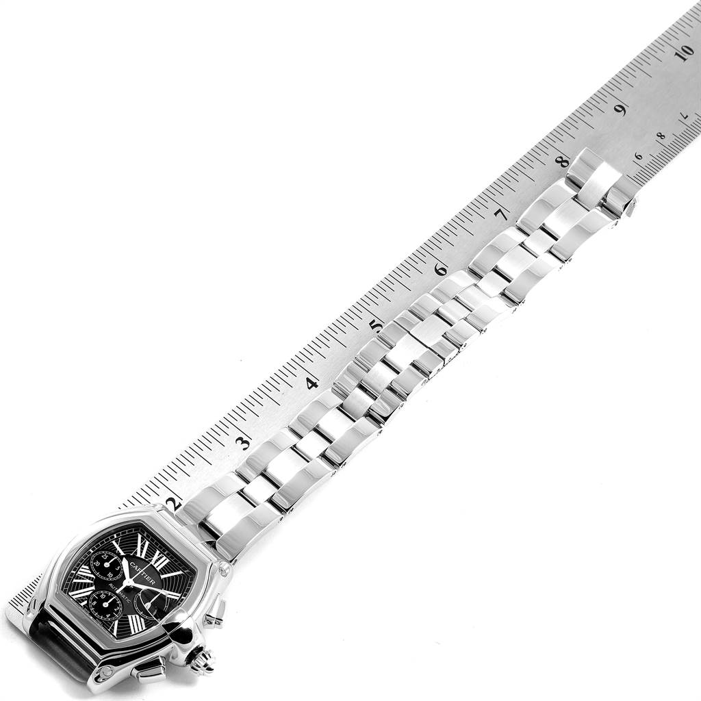 The image shows a Cartier Roadster W62020X6 Men's Stainless Steel Black Dial W62020X6 Men's Stainless Steel Black Dial watch against a ruler, highlighting its face, bracelet, and clasp from a top-down angle.