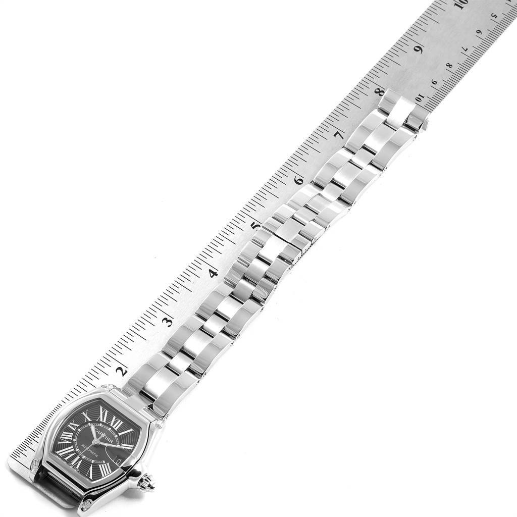 The image shows the Cartier Roadster W62041V3 Men's Stainless Steel Black Dial W62041V3 Men's Stainless Steel Black Dial watch laid flat next to a ruler, displaying the case, dial, and full bracelet.