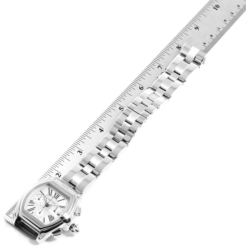 The image shows a Cartier Roadster W62019X6 Men
s Stainless Steel Silver Dial W62019X6 Men
s Stainless Steel Silver Dial watch laid diagonally with its full bracelet and part of a ruler for scale.
