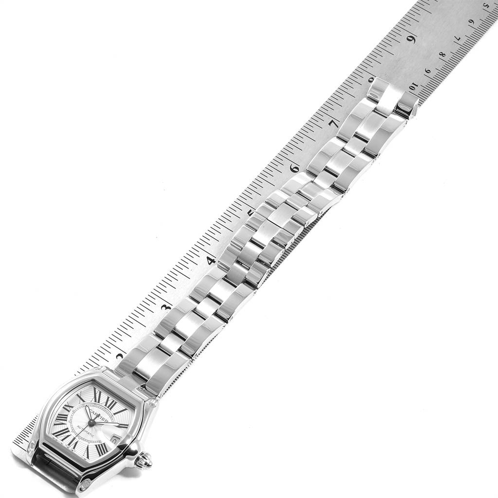 This image shows a Cartier Roadster W62025V3 Men
s Stainless Steel Silver Dial W62025V3 Men
s Stainless Steel Silver Dial watch laid flat next to a ruler, displaying its face and metal bracelet.