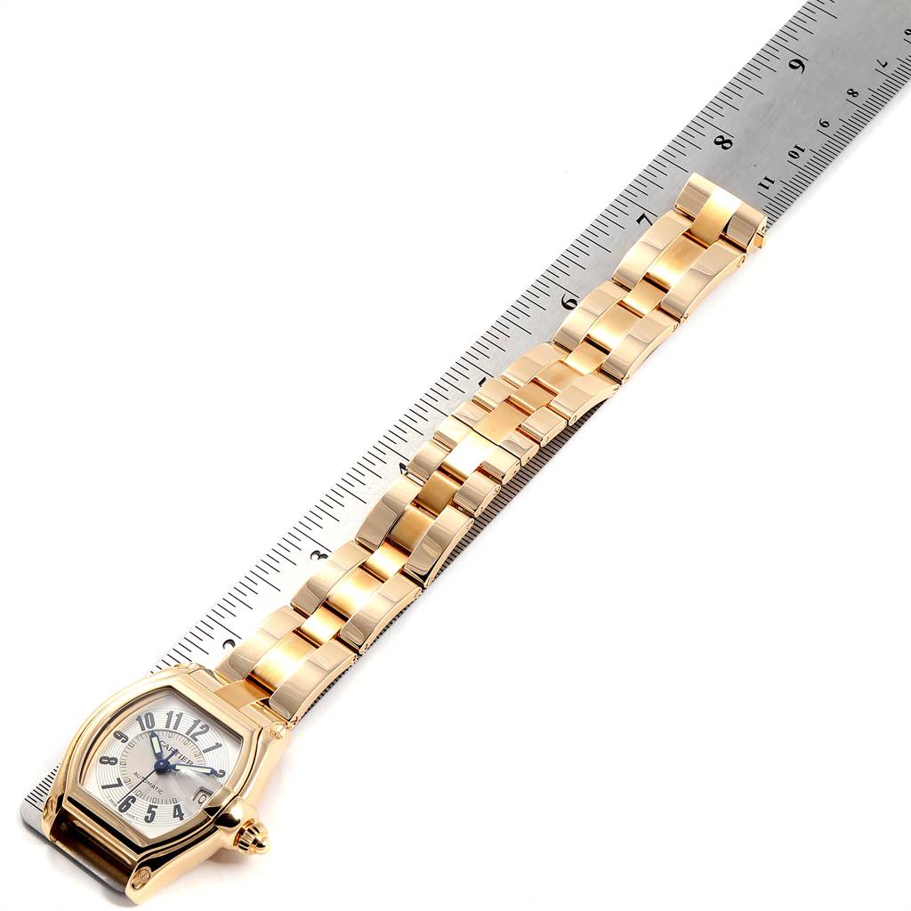 The Cartier Roadster W62003V1 Men
s Yellow Gold Silver Dial W62003V1 Men
s Yellow Gold Silver Dial watch is shown from an overhead angle, displaying the face and full metal bracelet next to a ruler.