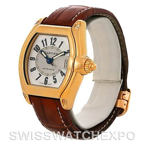 The image shows a Cartier Roadster W62005V2 Men's Yellow Gold Silver Dial W62005V2 Men's Yellow Gold Silver Dial watch displayed at an oblique angle, showcasing its dial, gold case, crown, and brown leather strap.