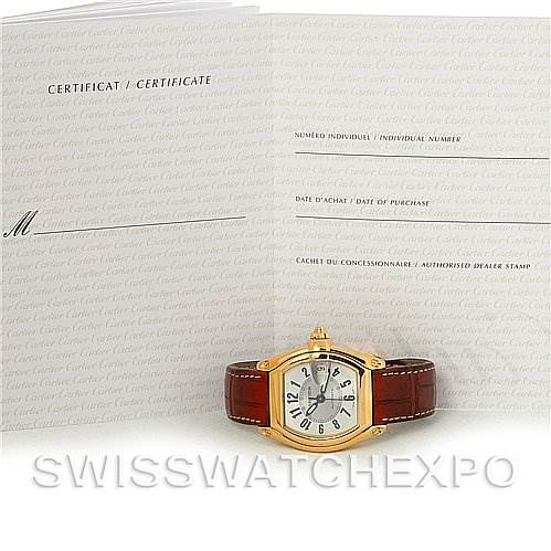 The image shows a Cartier Roadster W62005V2 Men's Yellow Gold Silver Dial W62005V2 Men's Yellow Gold Silver Dial watch with a certificate of authenticity in the background.