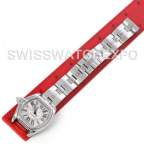 The image shows the Cartier Roadster W62025V3 Men's Stainless Steel Silver Dial W62025V3 Men's Stainless Steel Silver Dial watch lying flat on a red ruler, displaying its face and metal bracelet.