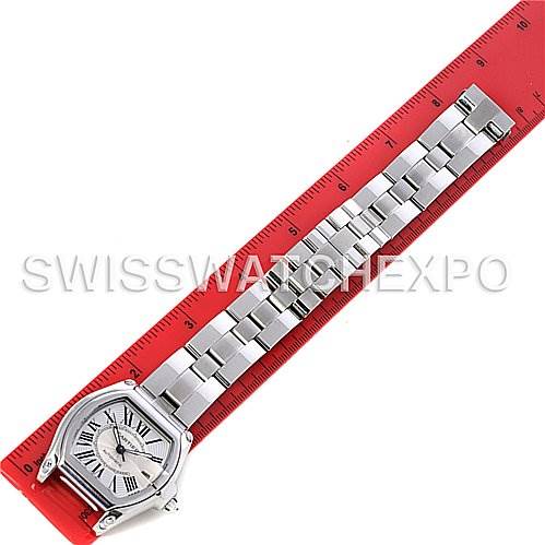The image shows a Cartier Roadster W62025V3 Men
s Stainless Steel Silver Dial W62025V3 Men
s Stainless Steel Silver Dial watch laid flat on a red ruler, displaying the watch face and full metal bracelet.
