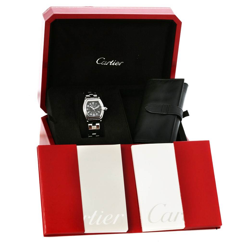 The Cartier Roadster W62004V3 Men's Stainless Steel Black Dial W62004V3 Men's Stainless Steel Black Dial watch is shown from the front, presented in its box with booklets and a black accessory case.