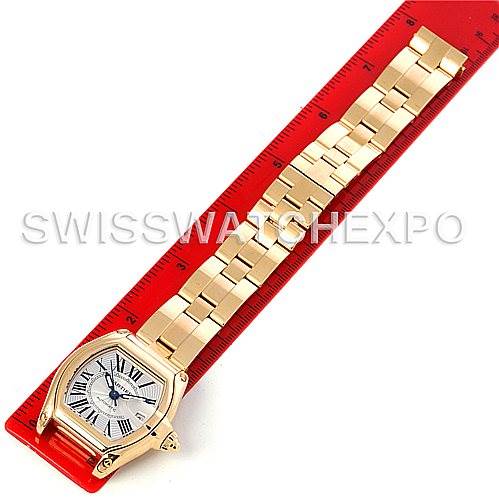 The image shows a Cartier Roadster W62005V1 Men
s Yellow Gold Silver Dial W62005V1 Men
s Yellow Gold Silver Dial watch laid flat against a red ruler, displaying its band and face from an overhead angle.
