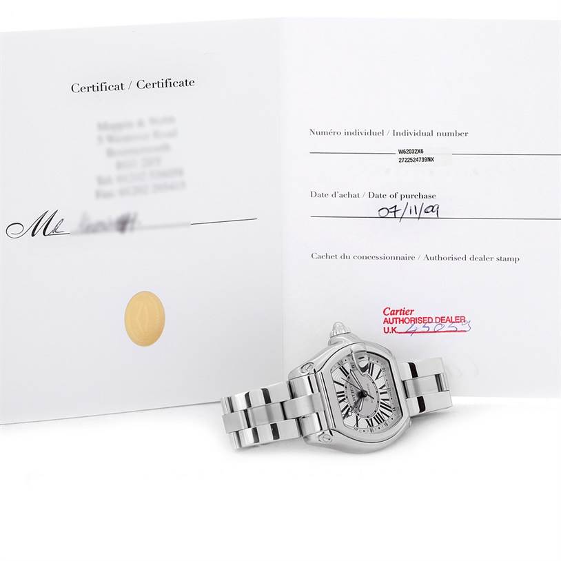 The image shows a Cartier Roadster W62032X6 Men's Stainless Steel Silver Dial W62032X6 Men's Stainless Steel Silver Dial watch from an angled top view along with its certificate of authenticity.
