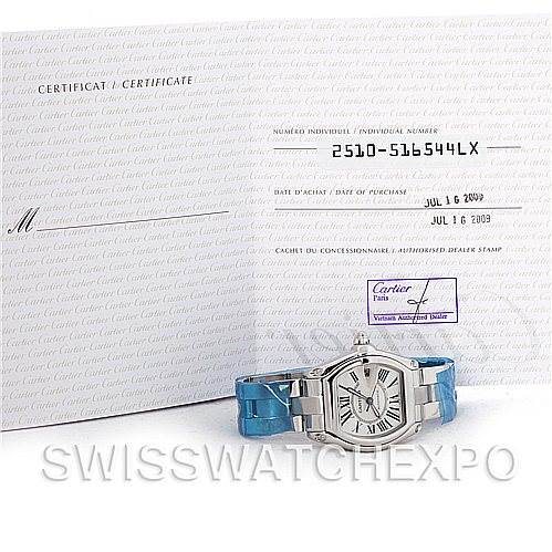 The image shows a frontal angle of a Cartier Roadster W62025V3 Men's Stainless Steel Silver Dial W62025V3 Men's Stainless Steel Silver Dial watch with its certificate in the background.