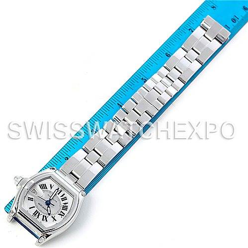 The image shows an overhead view of a Cartier Roadster W62025V3 Men's Stainless Steel Silver Dial W62025V3 Men's Stainless Steel Silver Dial watch with a metal bracelet next to a blue ruler for scale.