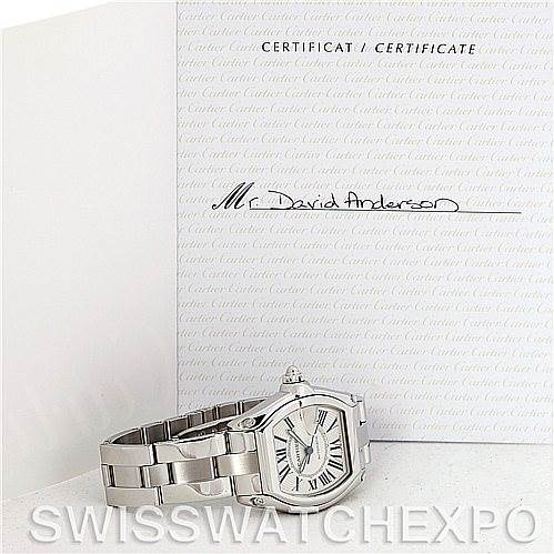The image shows a Cartier Roadster W62025V3 Men
s Stainless Steel Silver Dial W62025V3 Men
s Stainless Steel Silver Dial watch lying flat with its certificate of Best Quality
ity in the background.