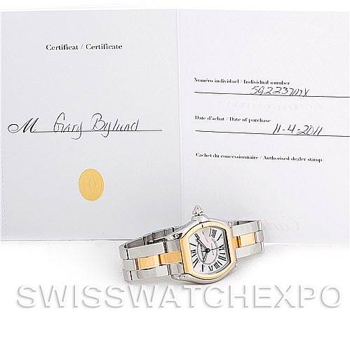 The Cartier Roadster W62031Y4 Men's Steel and Gold (two tone) Silver Dial W62031Y4 Men's Steel and Gold (two tone) Silver Dial watch is shown placed flat with its certificate of authenticity displayed behind it.
