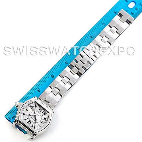 The image shows the Cartier Roadster W62025V3 Men's Stainless Steel Silver Dial W62025V3 Men's Stainless Steel Silver Dial watch, displaying the face and full bracelet, positioned next to a blue measuring ruler.