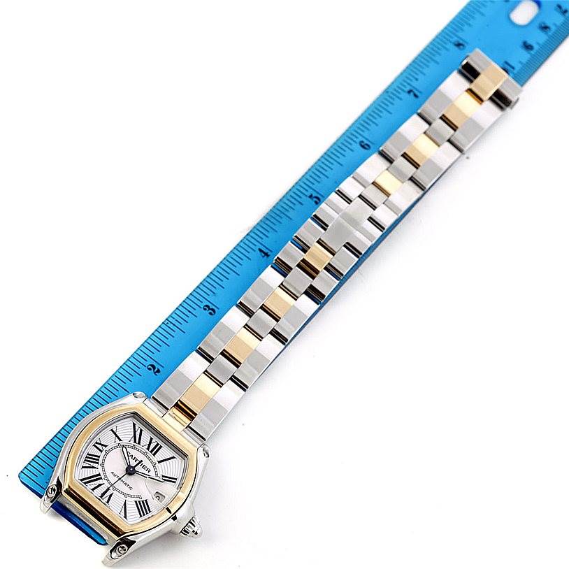 The Cartier Roadster W62031Y4 Men's Steel and Gold (two tone) Silver Dial W62031Y4 Men's Steel and Gold (two tone) Silver Dial watch is shown from a top-down angle, displaying its face and metal bracelet alongside a blue ruler.