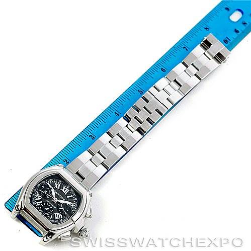 The Cartier Roadster W62007X6 Men
s Stainless Steel Black Dial W62007X6 Men
s Stainless Steel Black Dial watch is shown from a top-down angle, including the face and bracelet placed next to a blue ruler for scale.