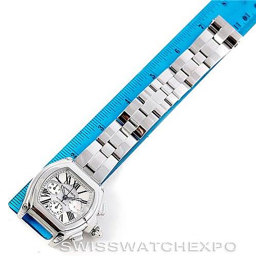 This image shows the Cartier Roadster W62019X6 Men's Stainless Steel Silver Dial W62019X6 Men's Stainless Steel Silver Dial watch laid flat next to a blue ruler, highlighting the face and full metal band.