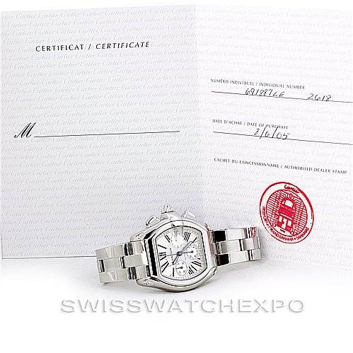 The image shows a Cartier Roadster W62019X6 Men's Stainless Steel Silver Dial W62019X6 Men's Stainless Steel Silver Dial watch along with its certificate of authenticity displayed at an angle.