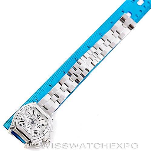The Cartier Roadster W62019X6 Men's Stainless Steel Silver Dial W62019X6 Men's Stainless Steel Silver Dial watch is shown from a top-down angle, displaying the face, bezel, and straightened bracelet against a blue ruler.