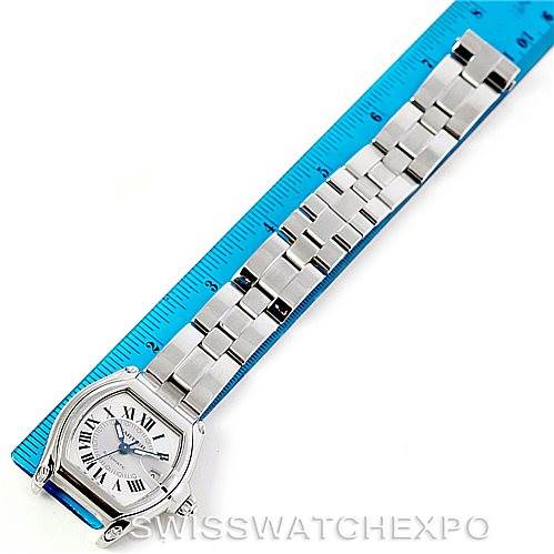 The image shows the Cartier Roadster W62025V3 Men's Stainless Steel Silver Dial W62025V3 Men's Stainless Steel Silver Dial watch from a top-down angle, including the face and full metal bracelet, alongside a blue ruler for scale.