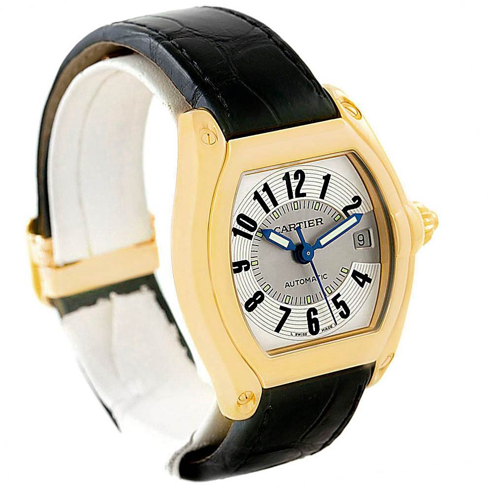 The image shows a Cartier Roadster W62005V2 Men's Yellow Gold Silver Dial W62005V2 Men's Yellow Gold Silver Dial watch from a front angle, showcasing its face, black leather strap, and gold casing.
