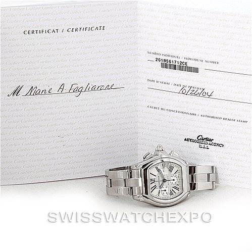 The image shows a Cartier Roadster W62019X6 Men's Stainless Steel Silver Dial W62019X6 Men's Stainless Steel Silver Dial watch at an angle with its face, bracelet, and accompanying certificate visible.