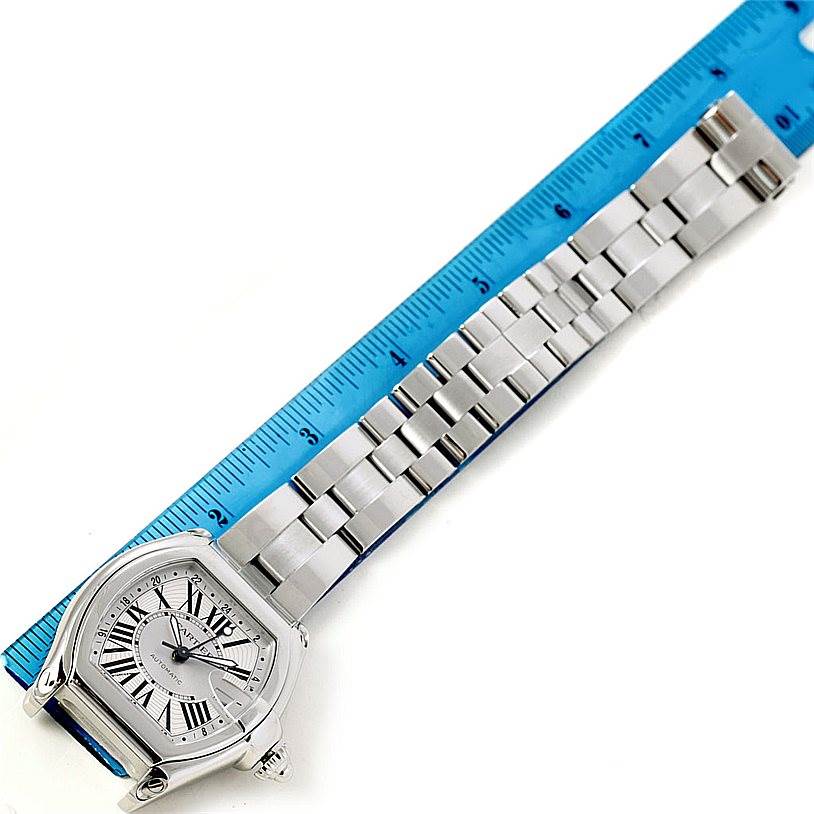 The image shows a top-down view of the Cartier Roadster W62032X6 Men's Stainless Steel Silver Dial W62032X6 Men's Stainless Steel Silver Dial watch, displaying the face and metal bracelet next to a blue ruler.