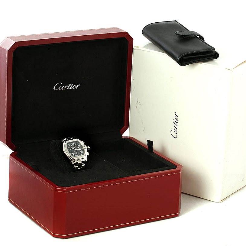 The Cartier Roadster W62020X6 Men's Stainless Steel Black Dial W62020X6 Men's Stainless Steel Black Dial watch is displayed at an angle in an open red Cartier box, with a white outer box and black leather pouch visible.