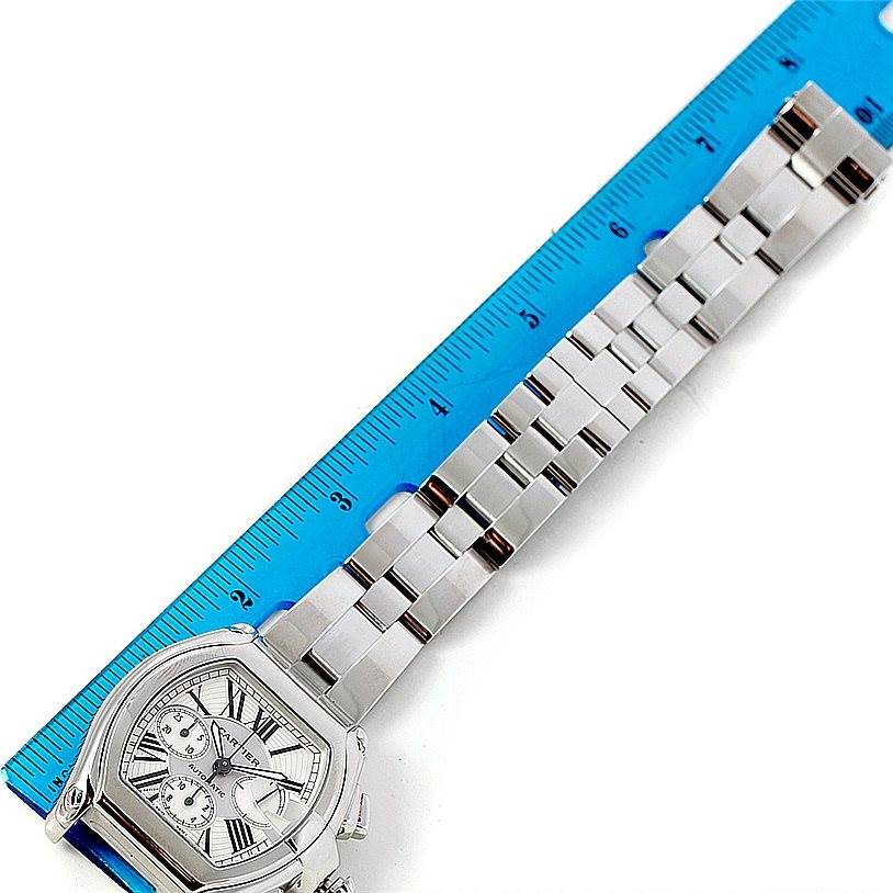 The Cartier Roadster W62019X6 Men
s Stainless Steel Silver Dial W62019X6 Men
s Stainless Steel Silver Dial watch is shown from an overhead angle, highlighting its face and metal bracelet alongside a ruler.