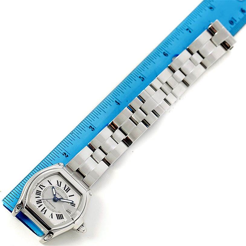 The image shows the face and full metal band of a Cartier Roadster W62000V3 Men's Stainless Steel Silver Dial W62000V3 Men's Stainless Steel Silver Dial watch placed next to a blue ruler.