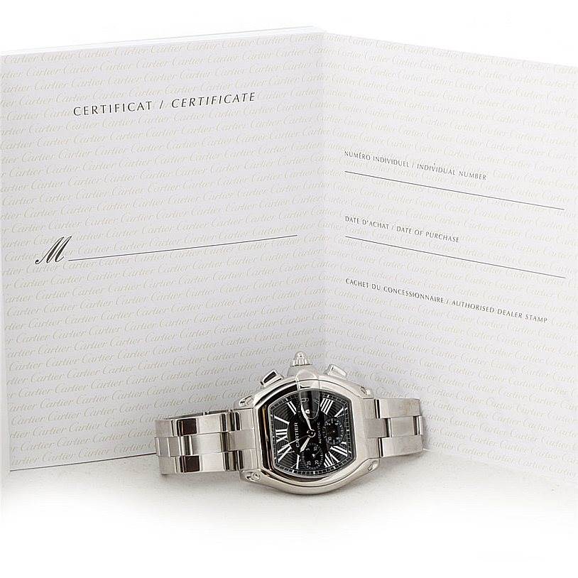 The image shows a Cartier Roadster W62020X6 Men's Stainless Steel Black Dial W62020X6 Men's Stainless Steel Black Dial watch laid flat with its certificate behind it.