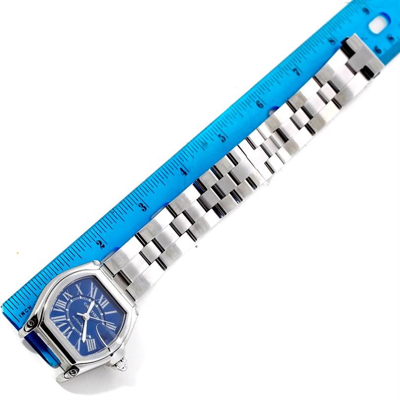 The image shows the front view of a Cartier Roadster W62048V3 Men's Stainless Steel Blue Dial W62048V3 Men's Stainless Steel Blue Dial watch alongside a ruler, highlighting the watch's face and bracelet.