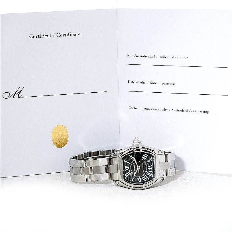 This image shows the Cartier Roadster W62041V3 Men's Stainless Steel Black Dial W62041V3 Men's Stainless Steel Black Dial watch from a front angle, featuring its certificate in the background.