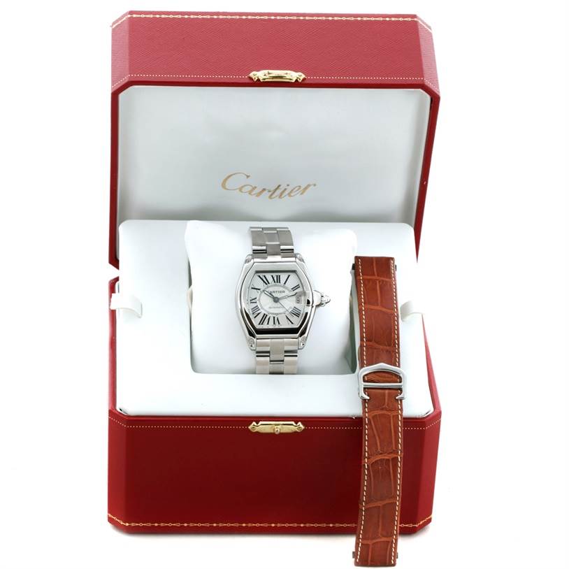 The image shows a Cartier Roadster W62025V3 Men's Stainless Steel Silver Dial W62025V3 Men's Stainless Steel Silver Dial watch face-on inside a red Cartier box, with an additional brown strap beside it.