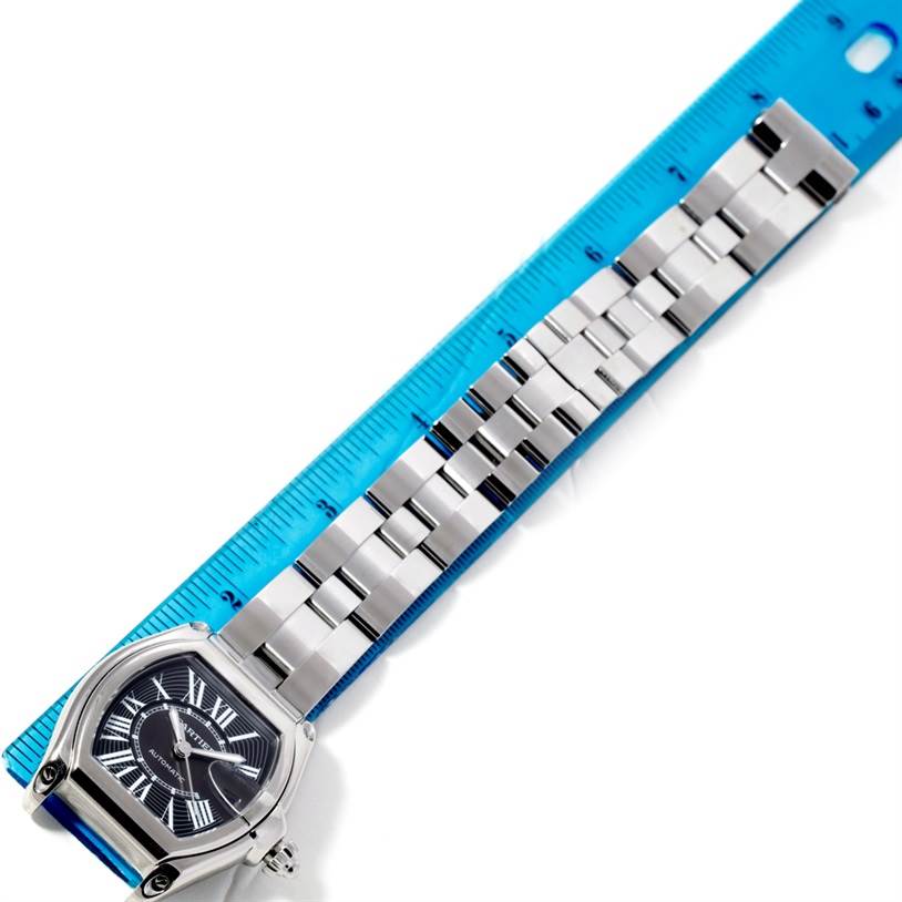 The image shows a Cartier Roadster W62041V3 Men's Stainless Steel Black Dial W62041V3 Men's Stainless Steel Black Dial watch at a top-down angle, featuring its face and metal bracelet, next to a blue ruler.