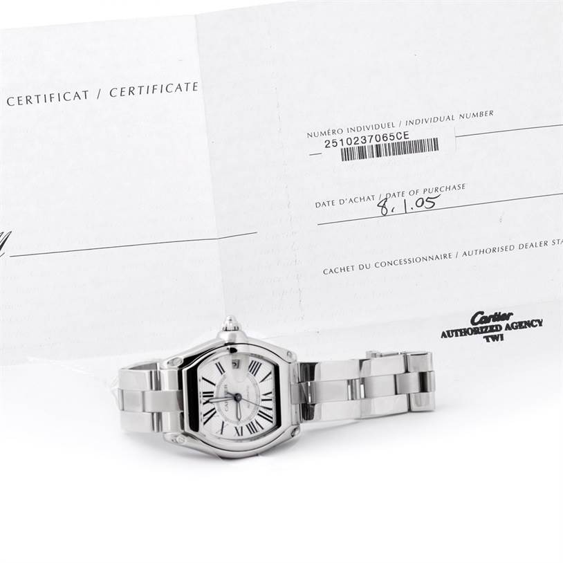 The image shows a Cartier Roadster W62025V3 Men
s Stainless Steel Silver Dial W62025V3 Men
s Stainless Steel Silver Dial watch laying flat with its certificate of Best Quality
ity in the background.