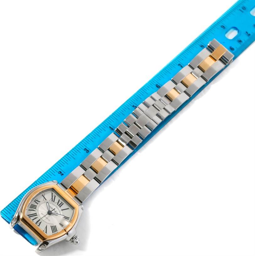 The Cartier Roadster W62031Y4 Men's Steel and Gold (two tone) Silver Dial W62031Y4 Men's Steel and Gold (two tone) Silver Dial watch is shown from above, highlighting the face and two-tone metal strap, next to a blue ruler.