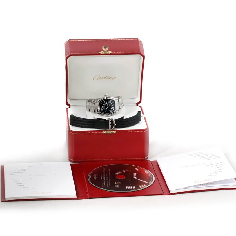 The image shows a Cartier Roadster W62041V3 Men's Stainless Steel Black Dial W62041V3 Men's Stainless Steel Black Dial watch in its box, accompanied by a black strap, documentation, and a CD.