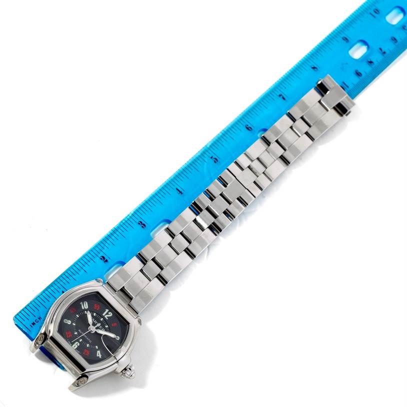 The image shows a Cartier Roadster W62002V3 Men
s Stainless Steel Black Dial W62002V3 Men
s Stainless Steel Black Dial watch placed next to a blue ruler, viewed from above, highlighting the watch face and metal bracelet.