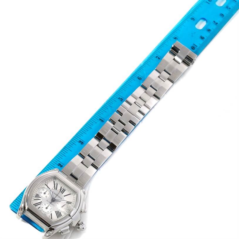 This image shows a top view of a Cartier Roadster W62019X6 Men's Stainless Steel Silver Dial W62019X6 Men's Stainless Steel Silver Dial watch placed against a blue ruler.